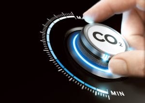 A hand turns a circular dial labeled CO₂, with glowing blue lights and markings ranging from MIN to MAX, symbolizing the adjustment of carbon dioxide levels.